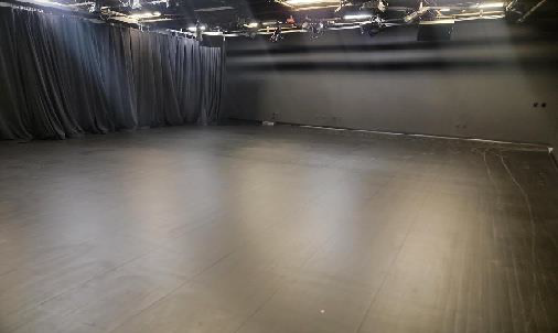 empty black box theater with black curtains, walls, and flooring