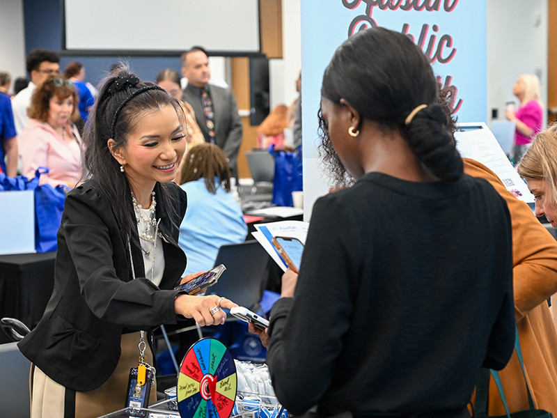 A City of Austin employee shows a potential employee how to sign up for a raffle at a job fair
