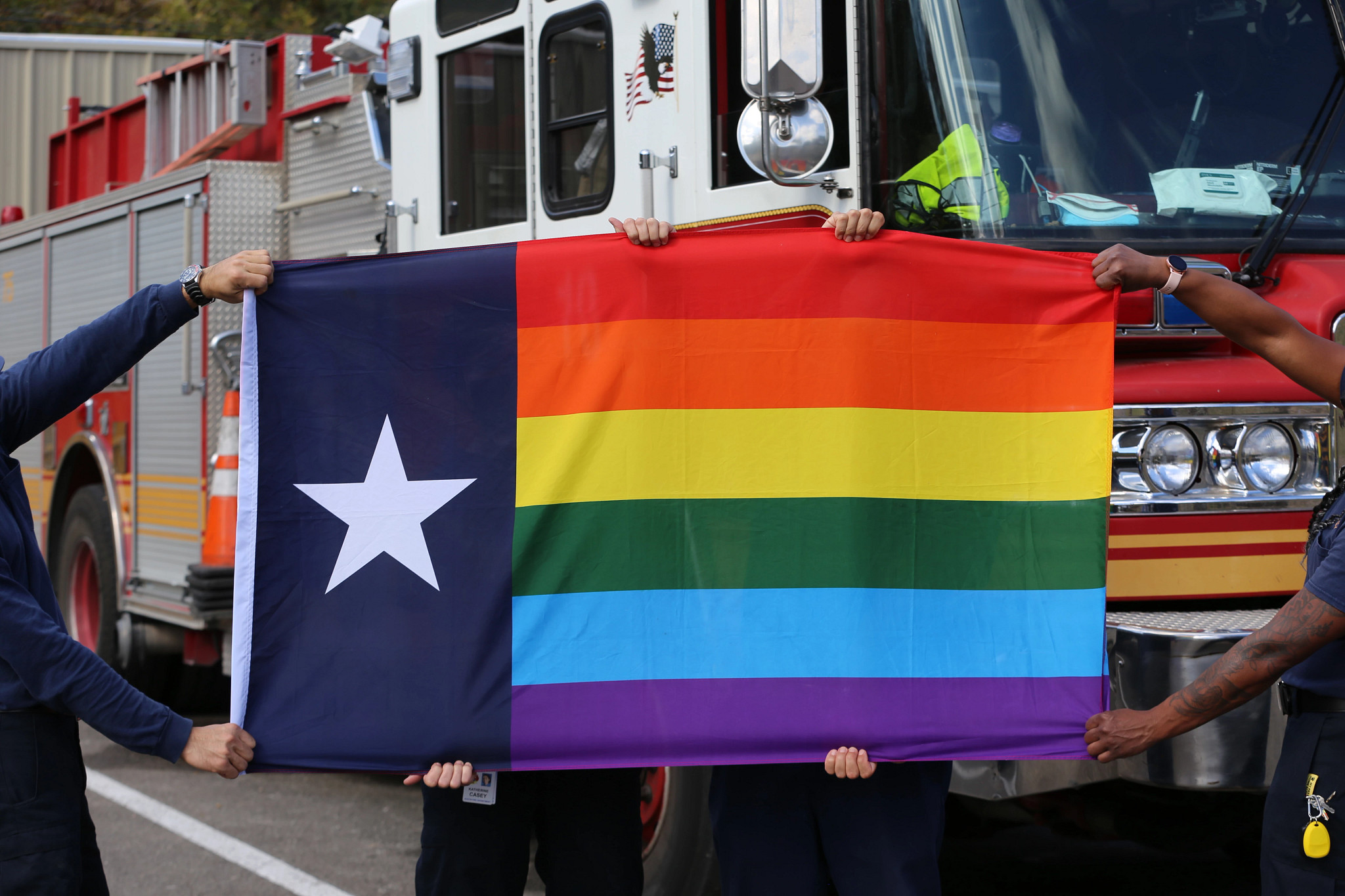 Texas LGBTQ+ flag held in front of an AFD truck