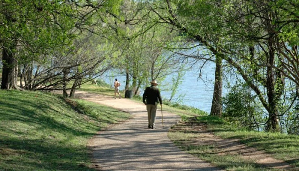 Image of walkers on town lake under tree cover.