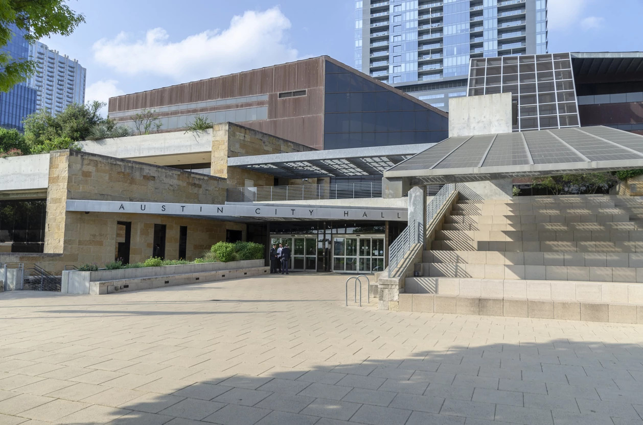 Exterior view of Austin City Hall featuring a paved plaza, stone facade, and terraced steps.