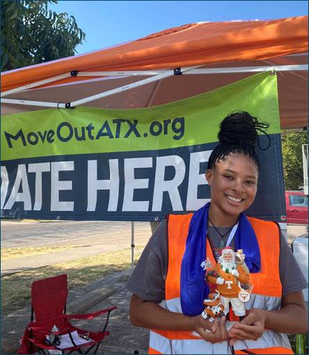 A young woman posing with donated items under a tent.