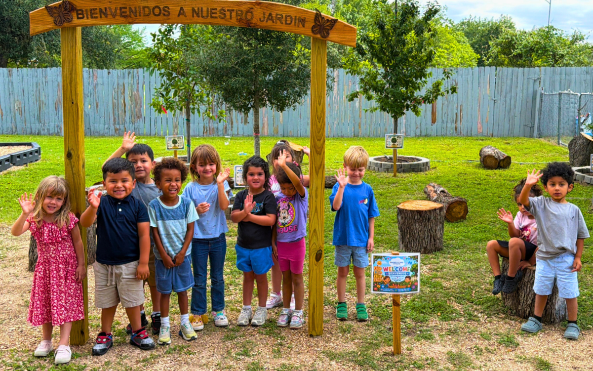 Students stand beneath a new wooden arch in Angel Care and Learning Center's outdoor classroom.