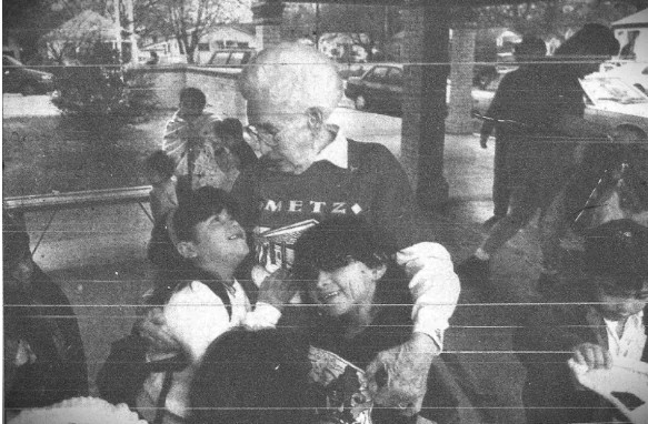 Older woman hugging two youth female in a library