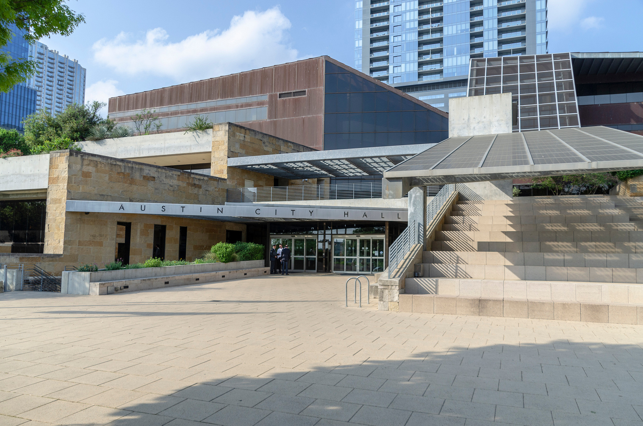 Exterior view of Austin City Hall featuring a paved plaza, stone facade, and terraced steps