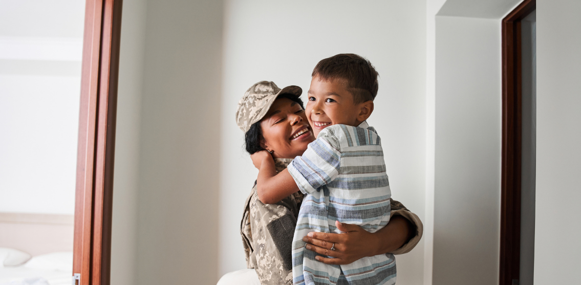 Image of a woman in military uniform embracing a child.