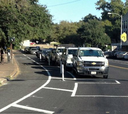 Vehicles parking along a street with a protected bike lane in Austin.