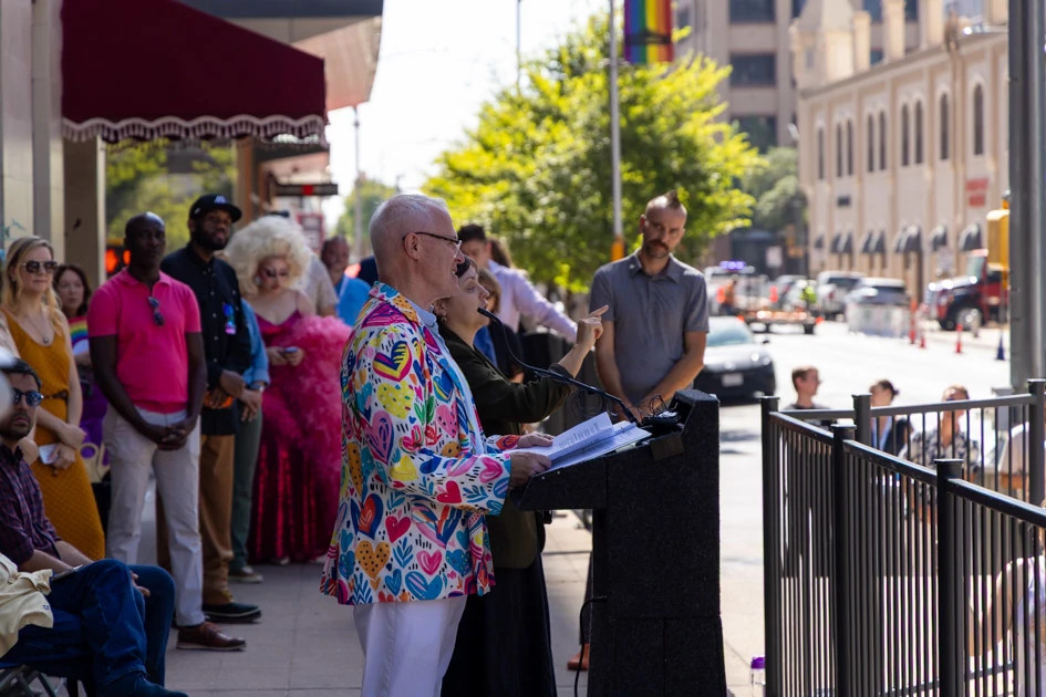 Person speaks at a podium outside in front of a crowd