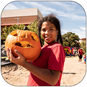 Child holding a pumpkin at Pumpkin Carver 