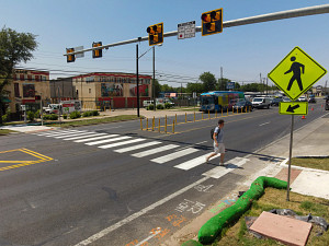 A person crosses at a pedestrian hybrid beacon, which prompted vehicular traffic to stop on a five-lane street with bike lanes.