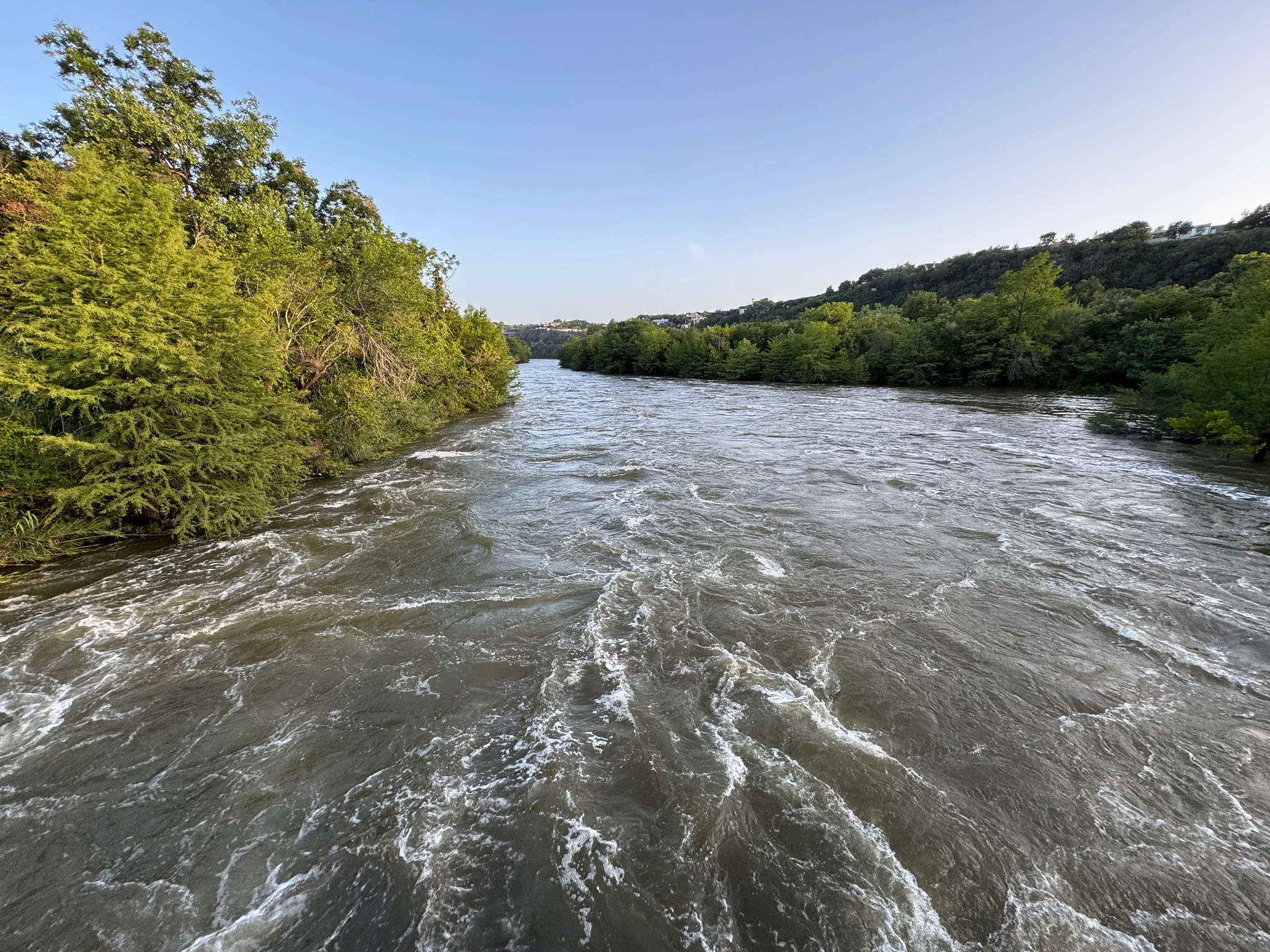 photo of fast-running river water with trees on the banks