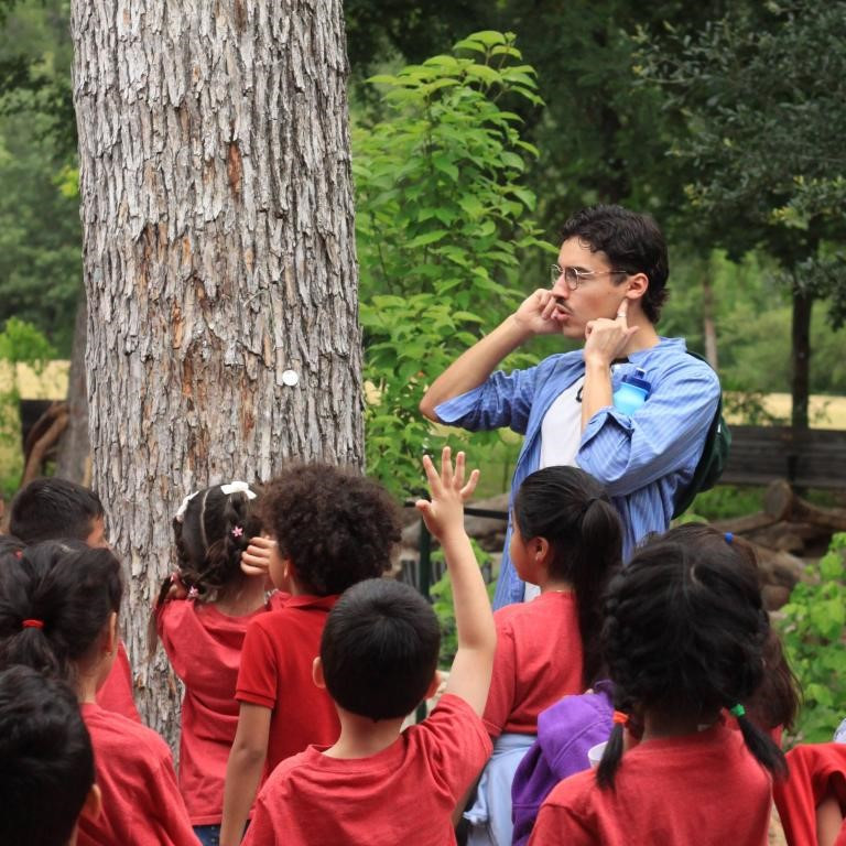 A Pease Park Conservancy staffer speaks to children on a field trip