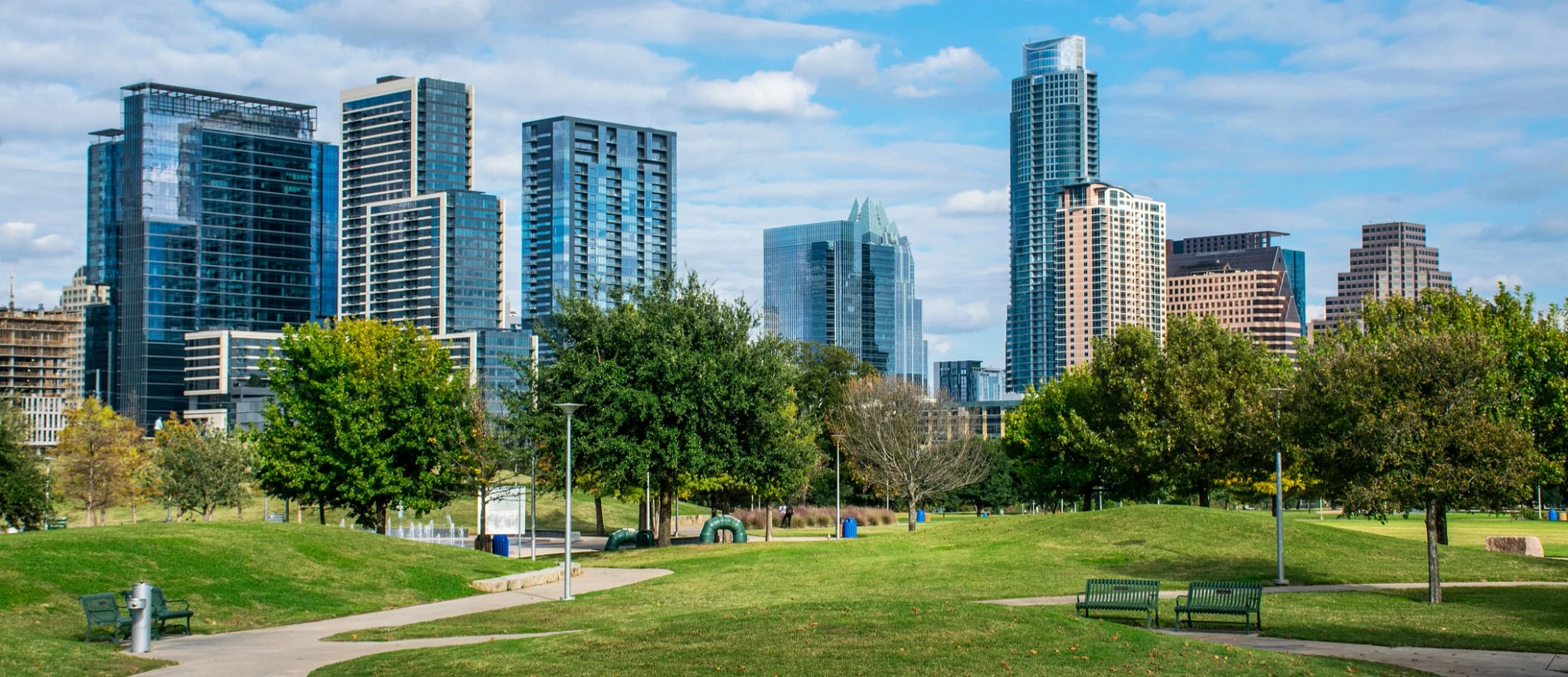 A park on a sunny day with cityscape of Austin Texas in the background.