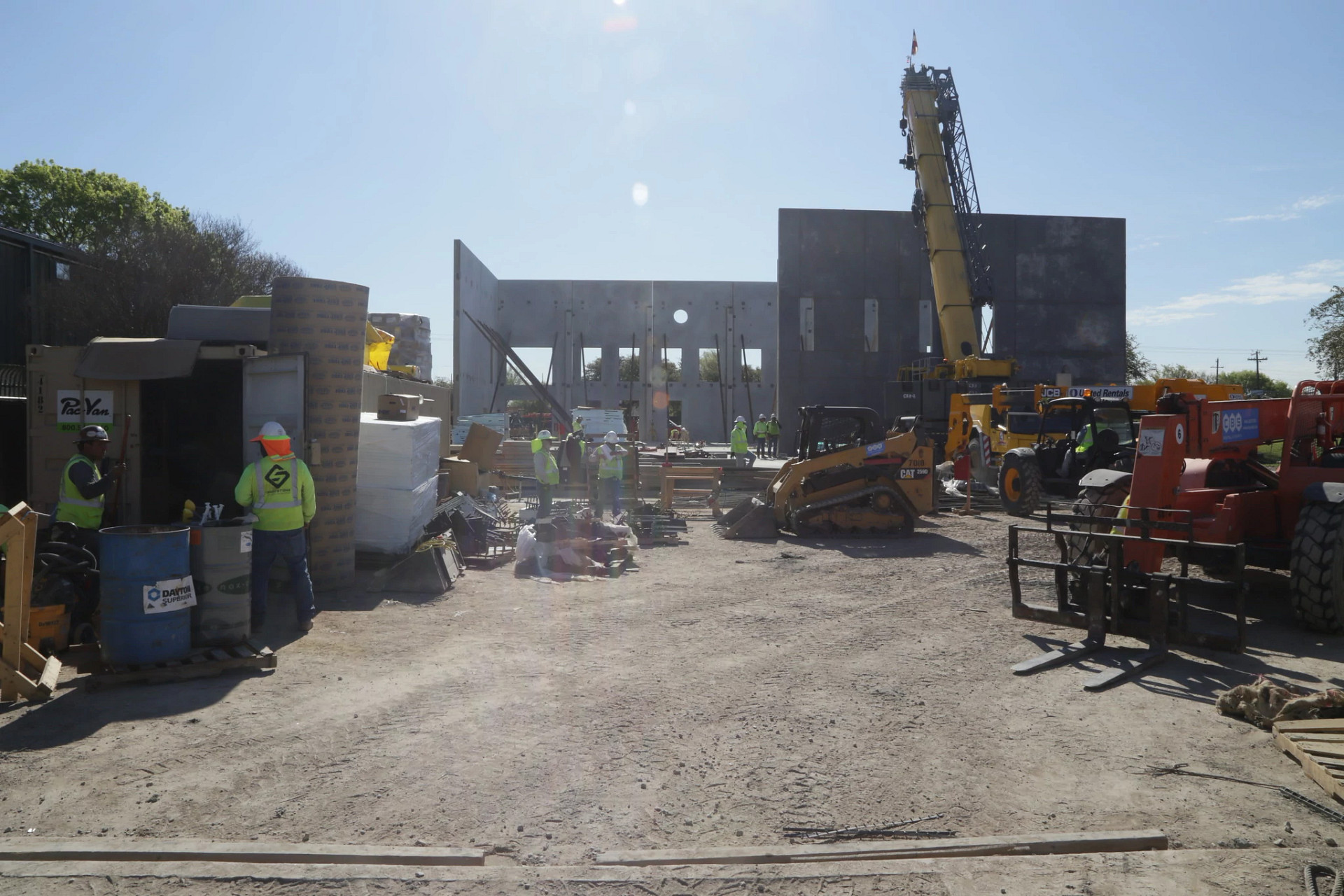 Construction workers and heavy equipment at the Montopolis Recreation and Community Center site as large concrete wall panels are installed.
