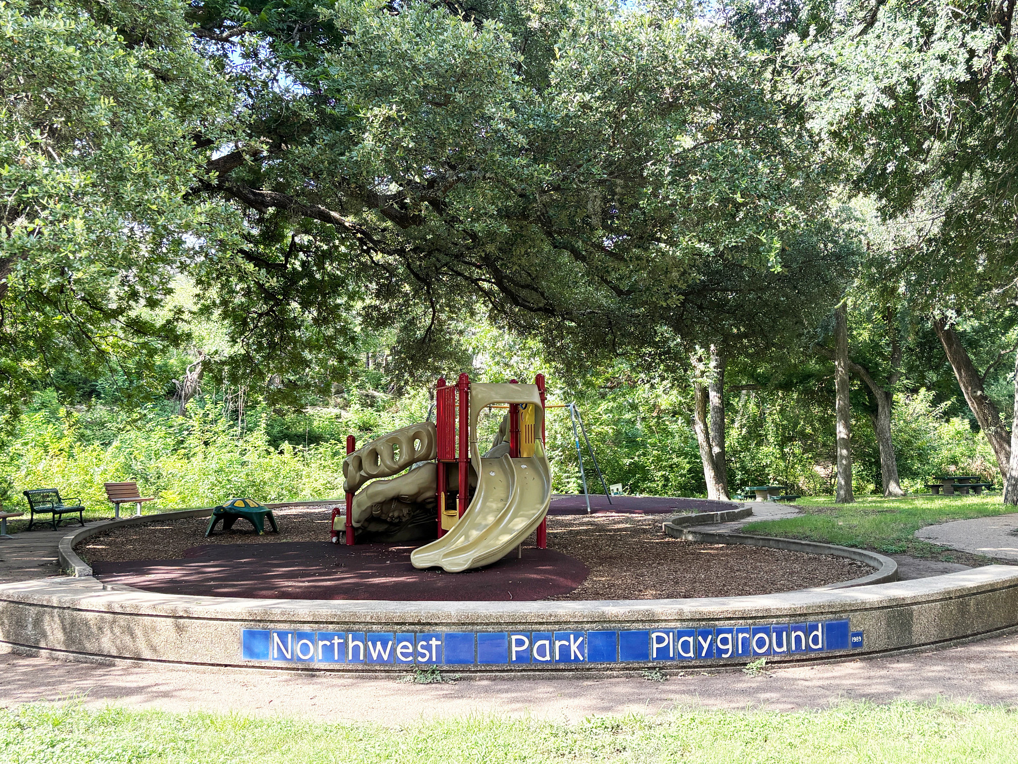 Beverly S. Sheffield Northwest Park playscape for ages 5 to 12 showing slides and trees in background