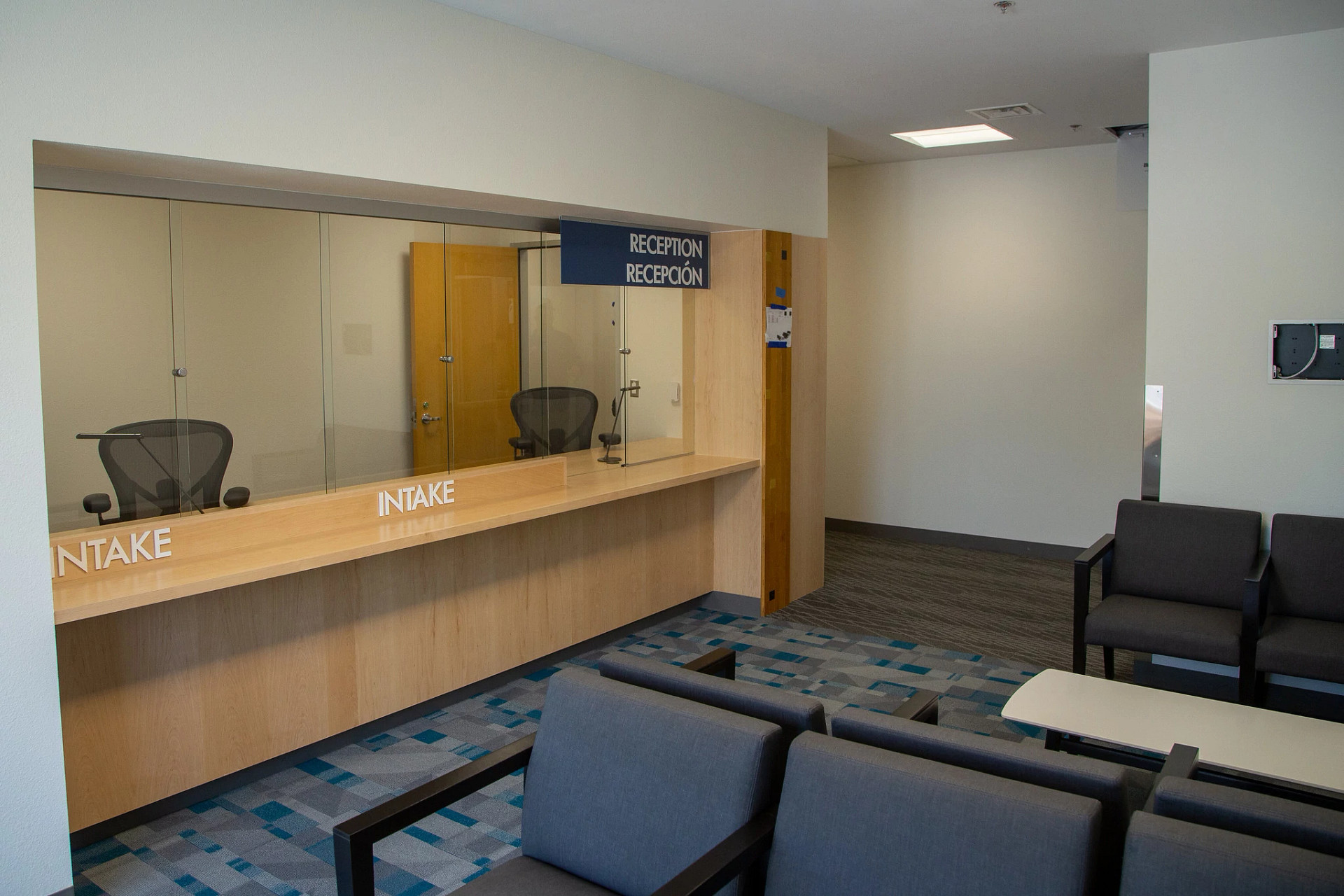 Reception and intake area inside the Montopolis Recreation and Community Center, with a glass-enclosed service counter and seating area.