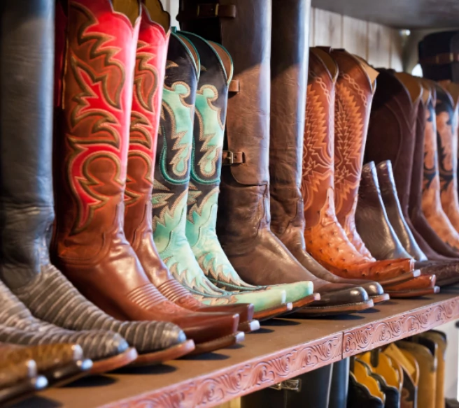 close up photograph of multiple pairs of cowboy boots on a shelf