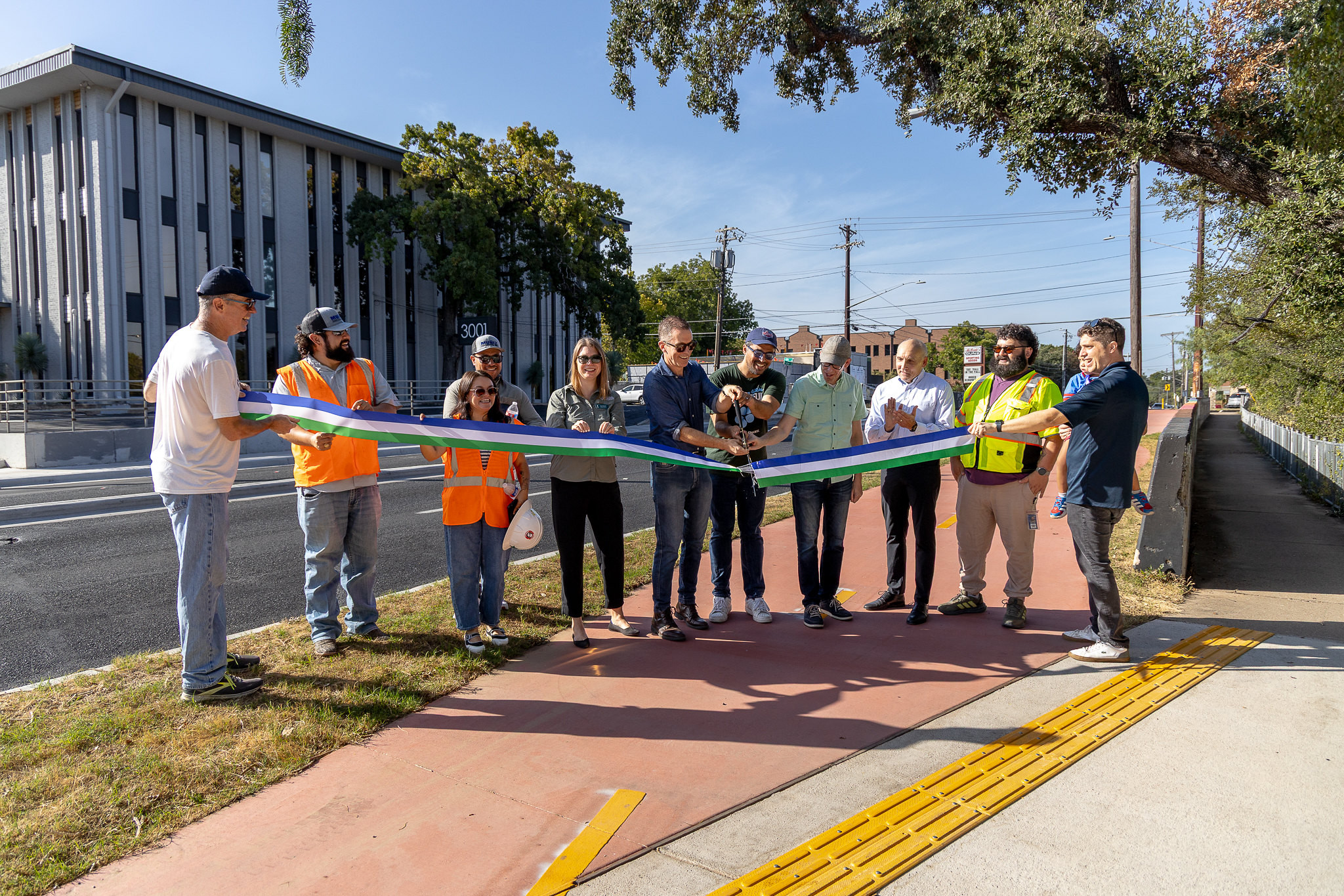 Photo of City Council Members, community advocates and City of Austin Staff cutting a ribbon to celebrate the Shoal Creek Trail "middle gap" completion.