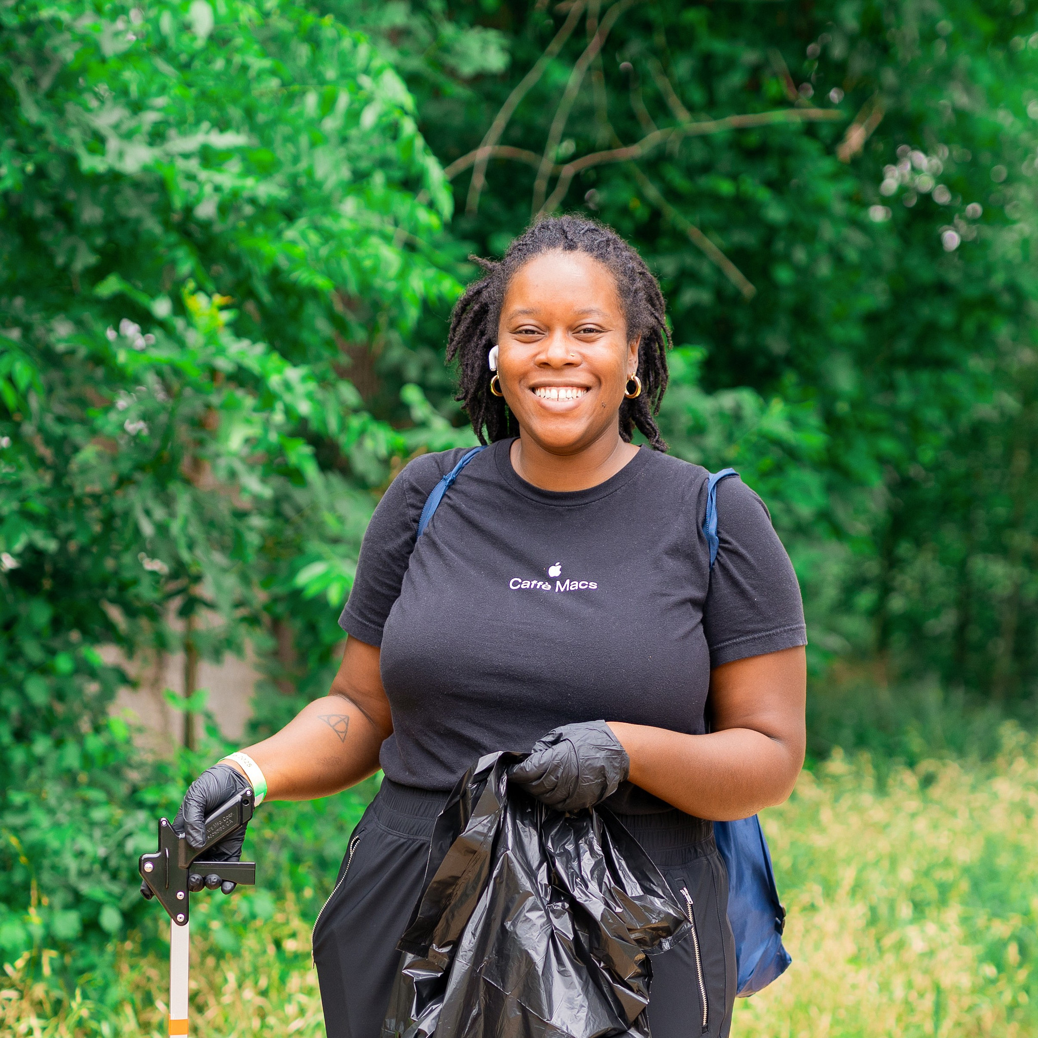 A volunteer picks up litter on a trail
