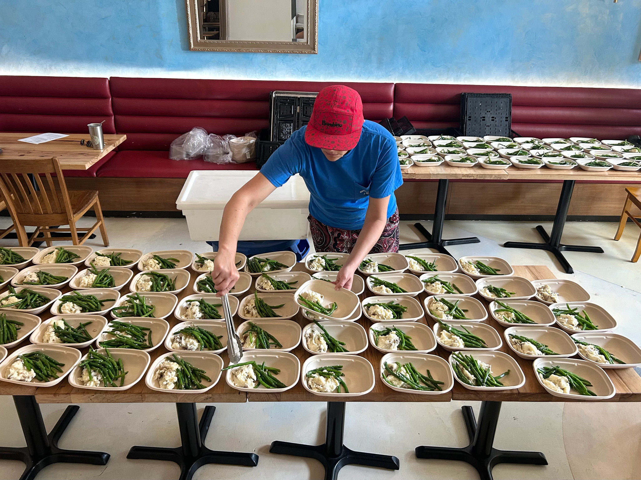L’Oca d’Oro employee prepares carry-out meals in compostable packaging.