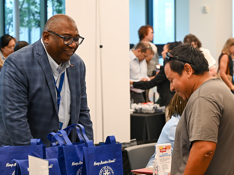 A potential employee and City of Austin employee looking at gift bags at a City of Austin job fair