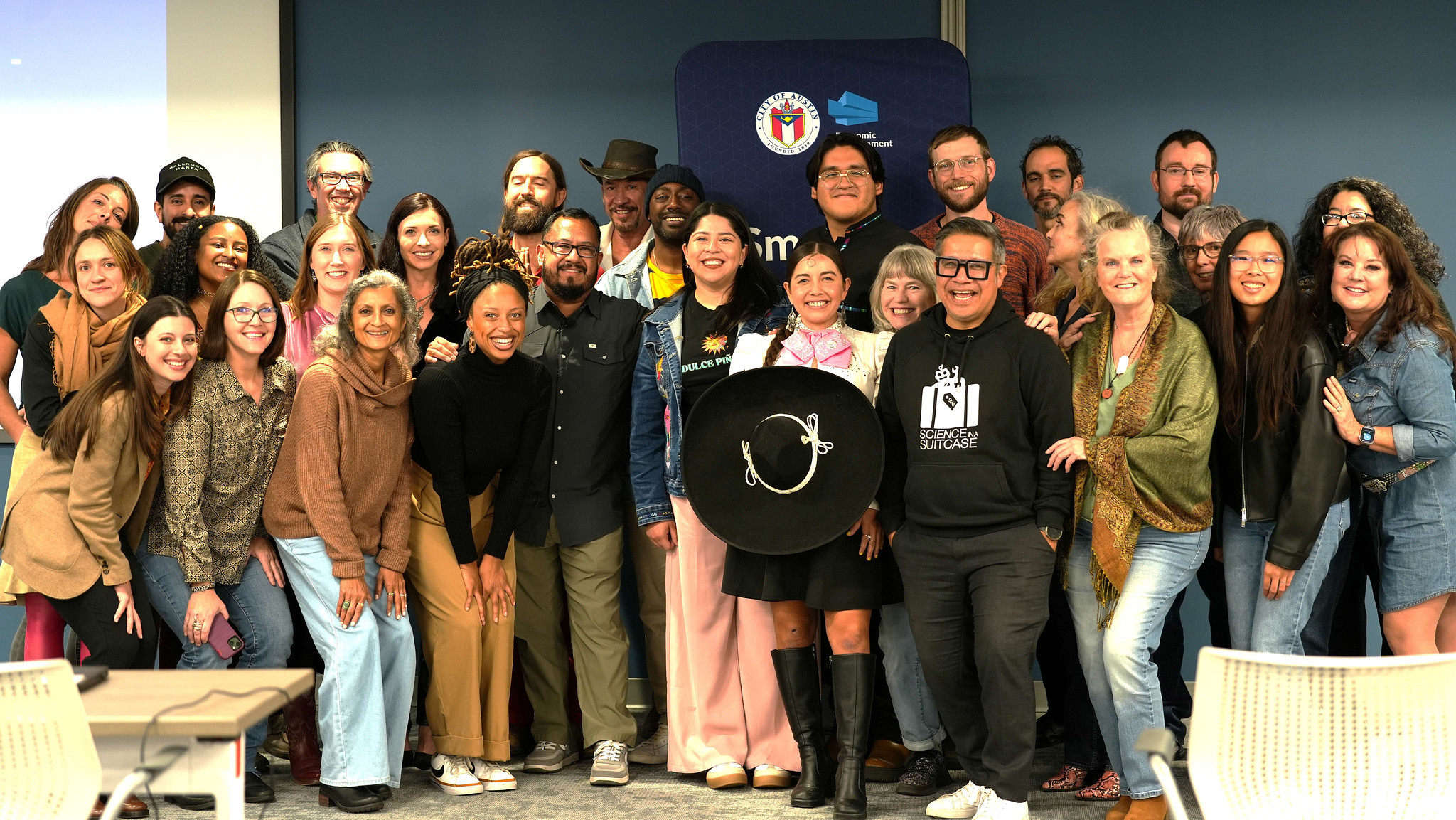 A group of creative students gather around for a photo.