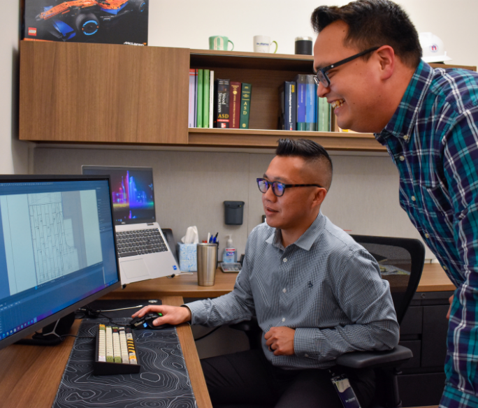 Two staff members reviewing building plans on a computer screen