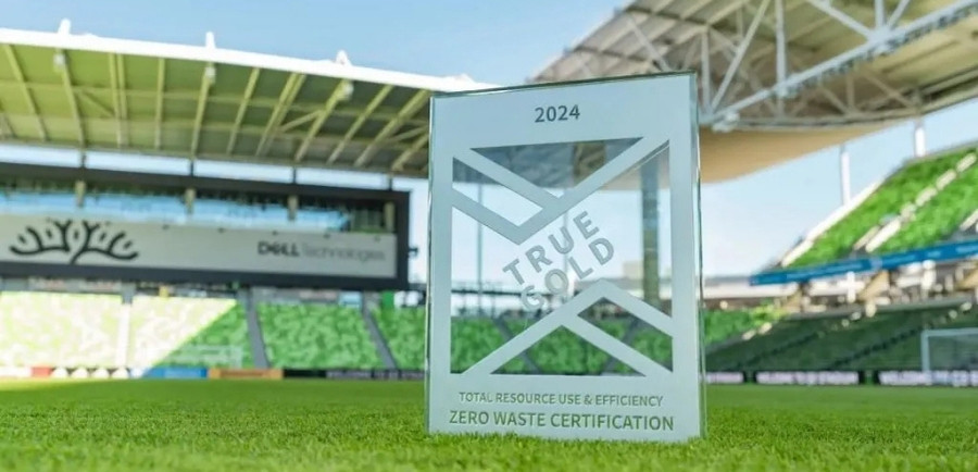 The TRUE GOLD Certification Plaque stands on the field in the Austin FC stadium.