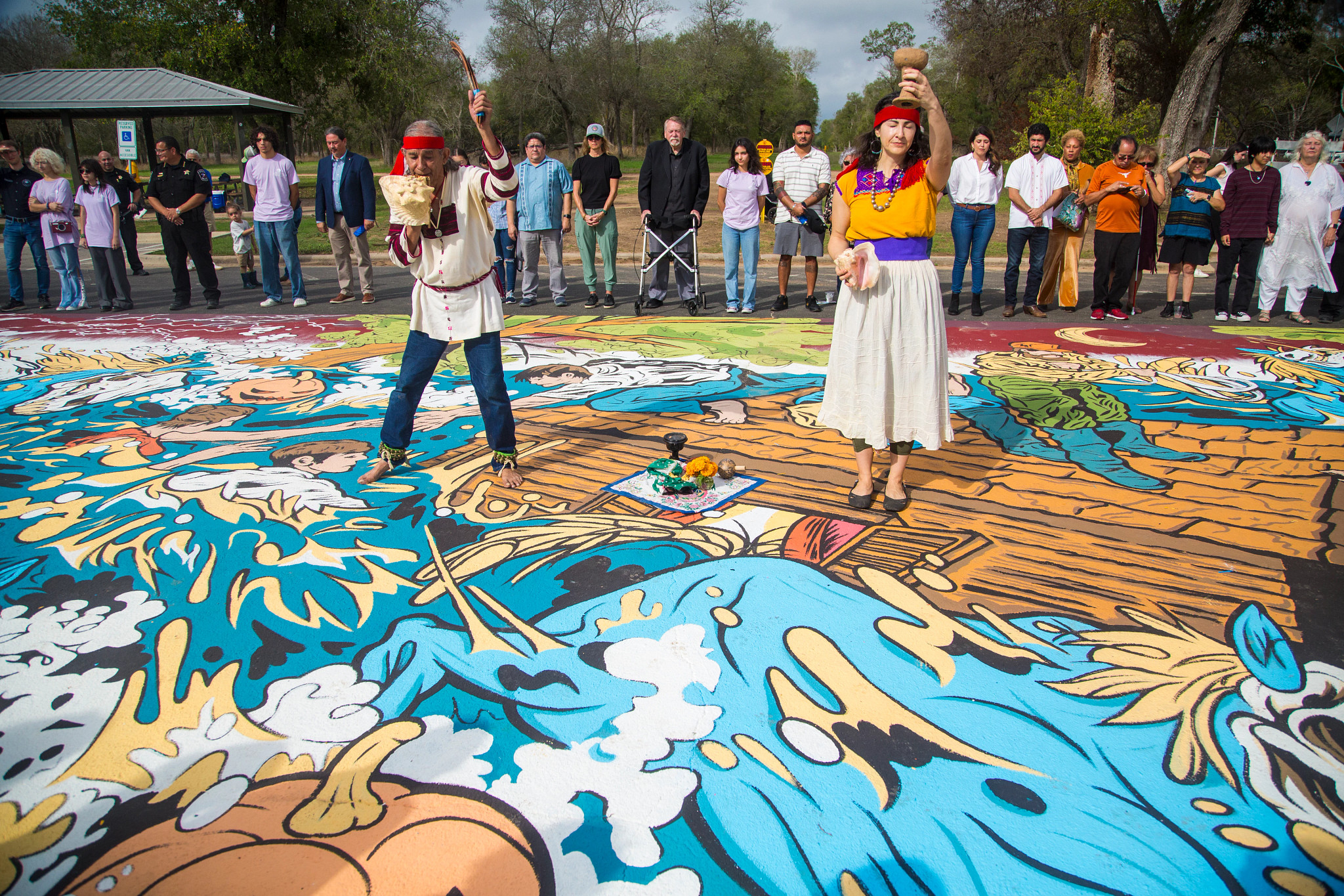 People dancing on top of a mural on asphalt