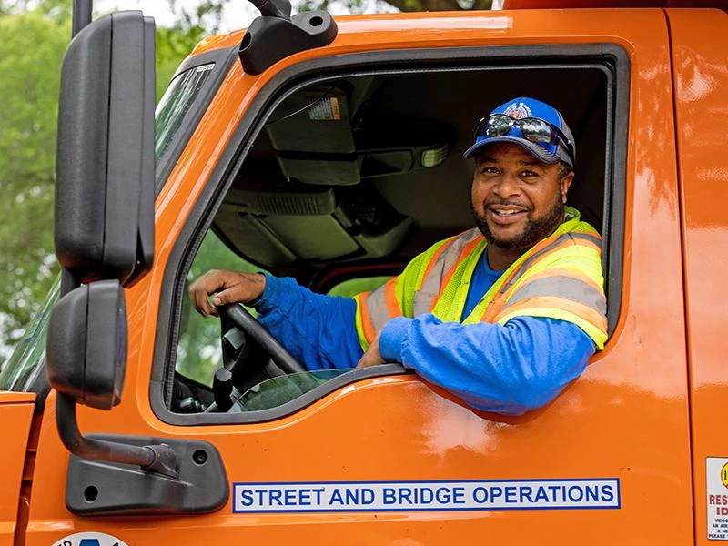 Smiling City of Austin employee driving a Street and Bridge operations truck