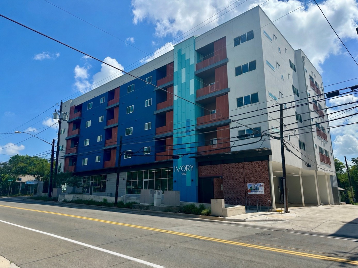 Exterior view of The Ivory, a mixed-use condominium building with blue, white, and teal accents located in Austin