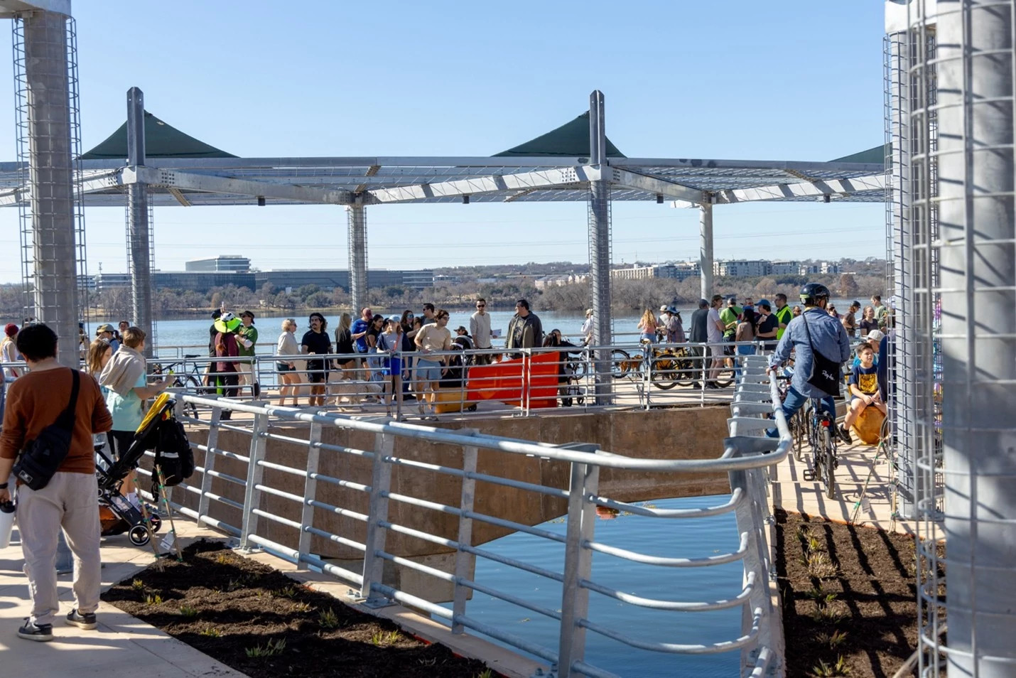 People gather underneath the shade structures in the plaza at the center of the bridge. Photo by Austin Transportation and Public Works.