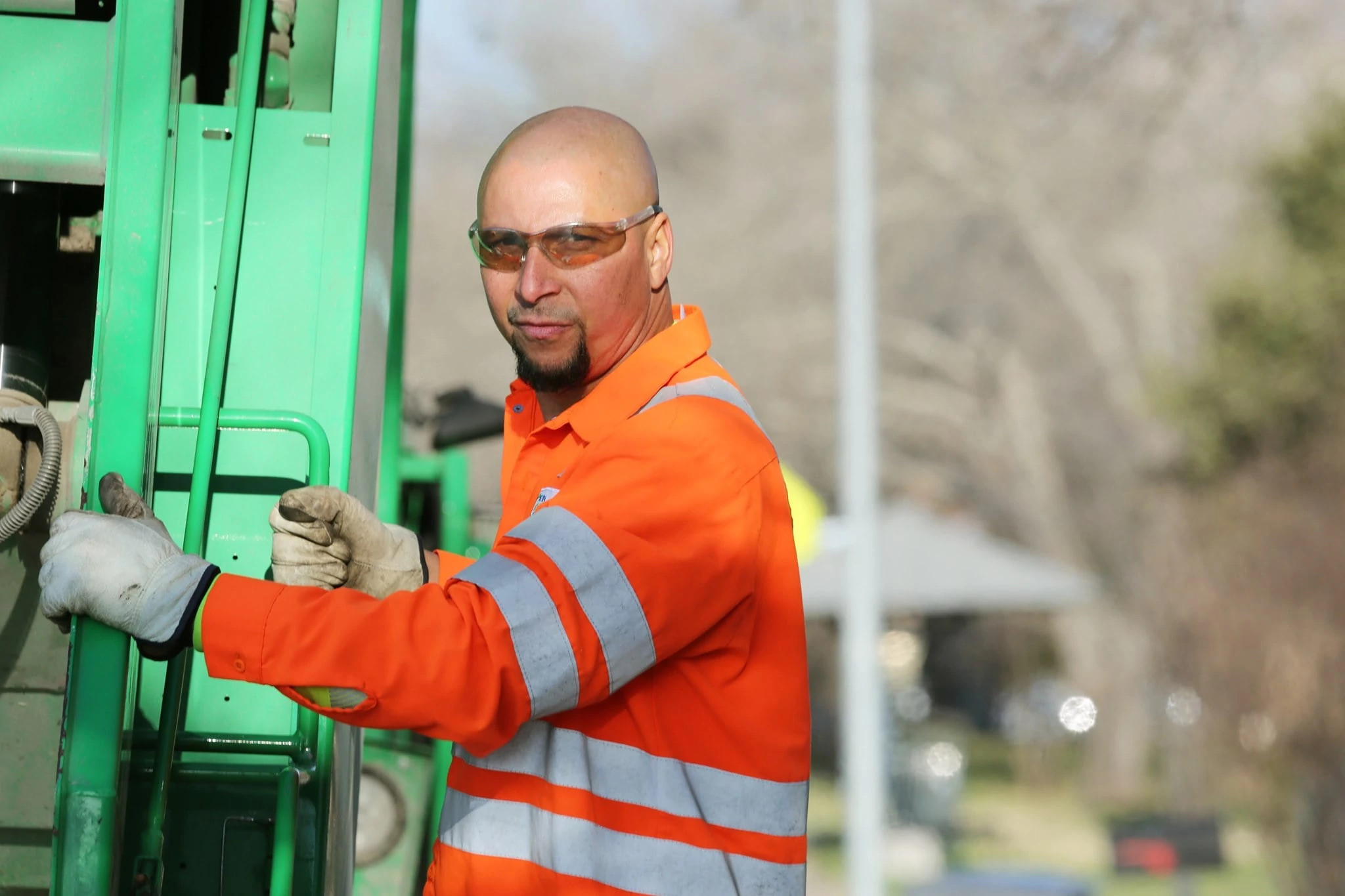 Sanitation worker rides on the back of a collection truck