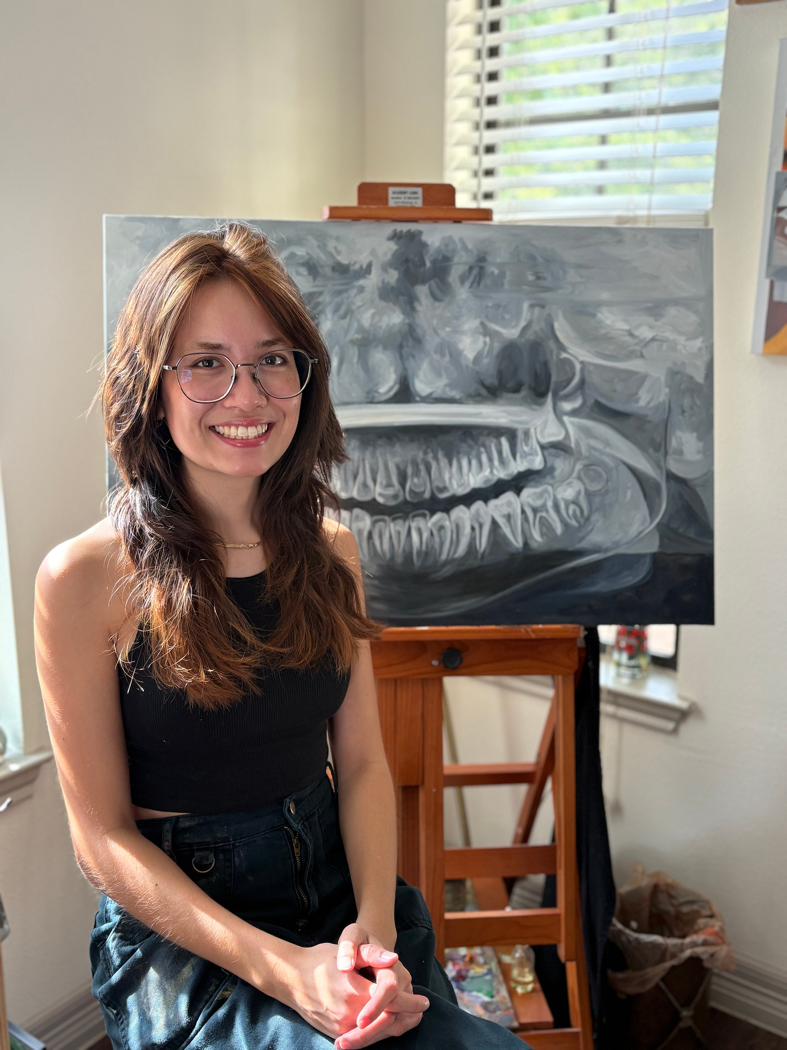 Picture of Gabrielle Clemente sitting in front of a piece from Frottage, smiling at the calendar