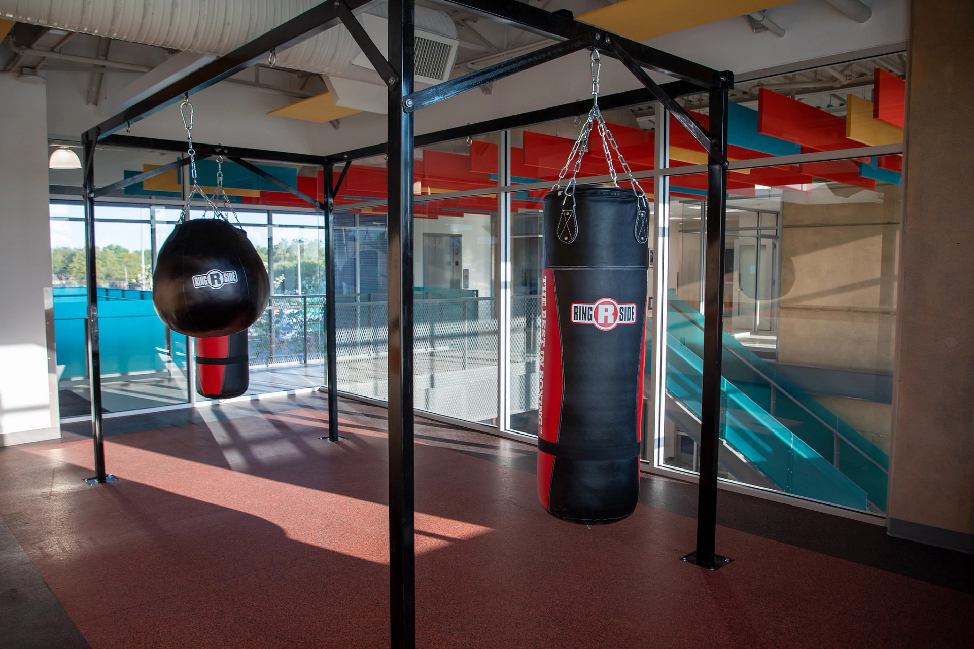 Boxing area inside the Montopolis Recreation and Community Center with two punching bags suspended from black metal frames.