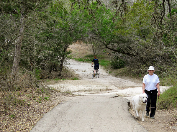Man walking a dog on a leash and bicycle rider at Mary Moore Searight Metropolitan Park