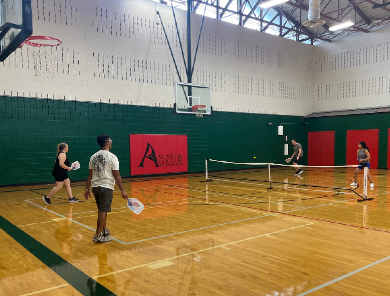 Four people playing pickleball indoors at an Austin recreation center