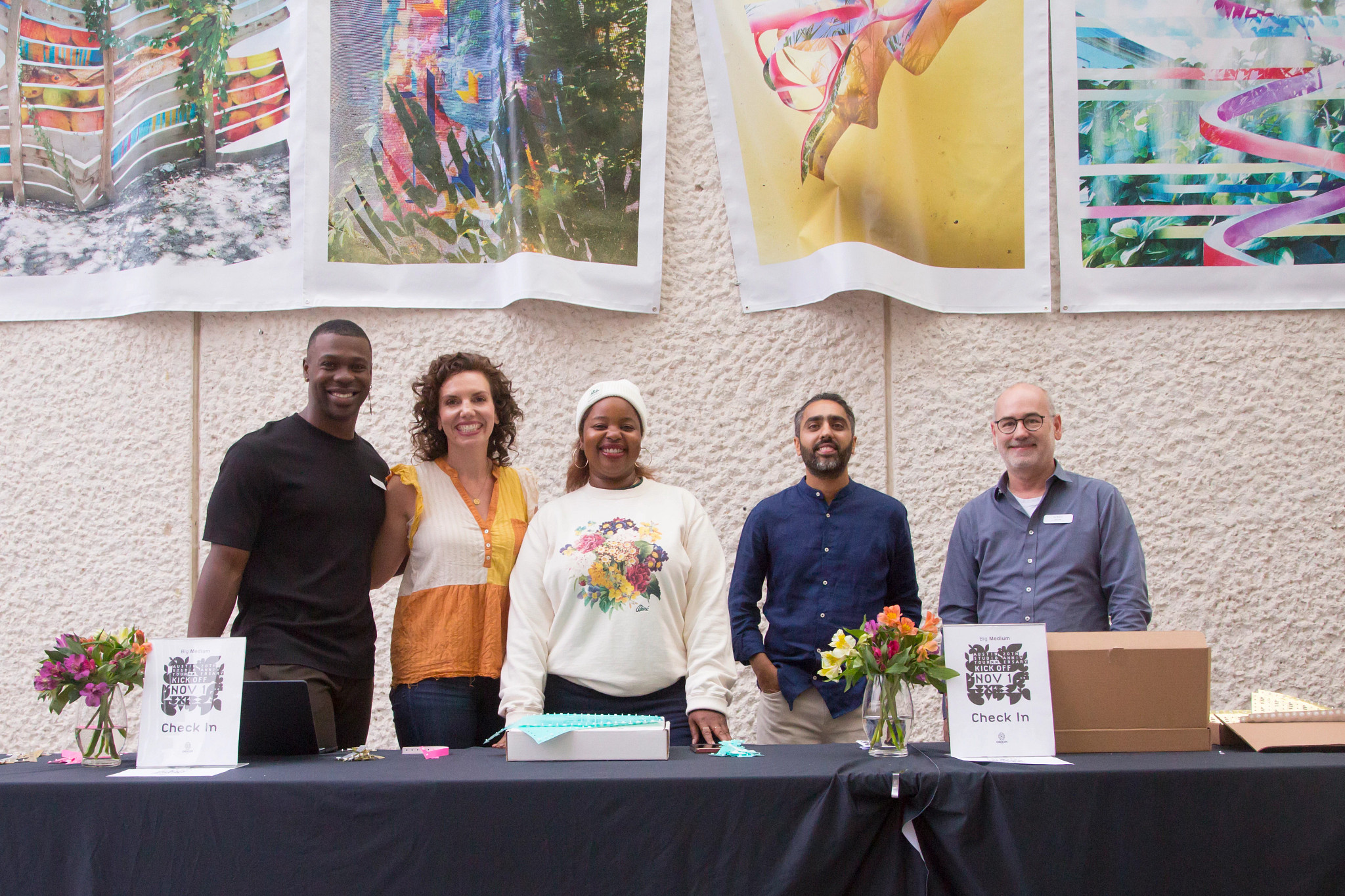 A group of people standing behind a welcome table and smiling at the camera