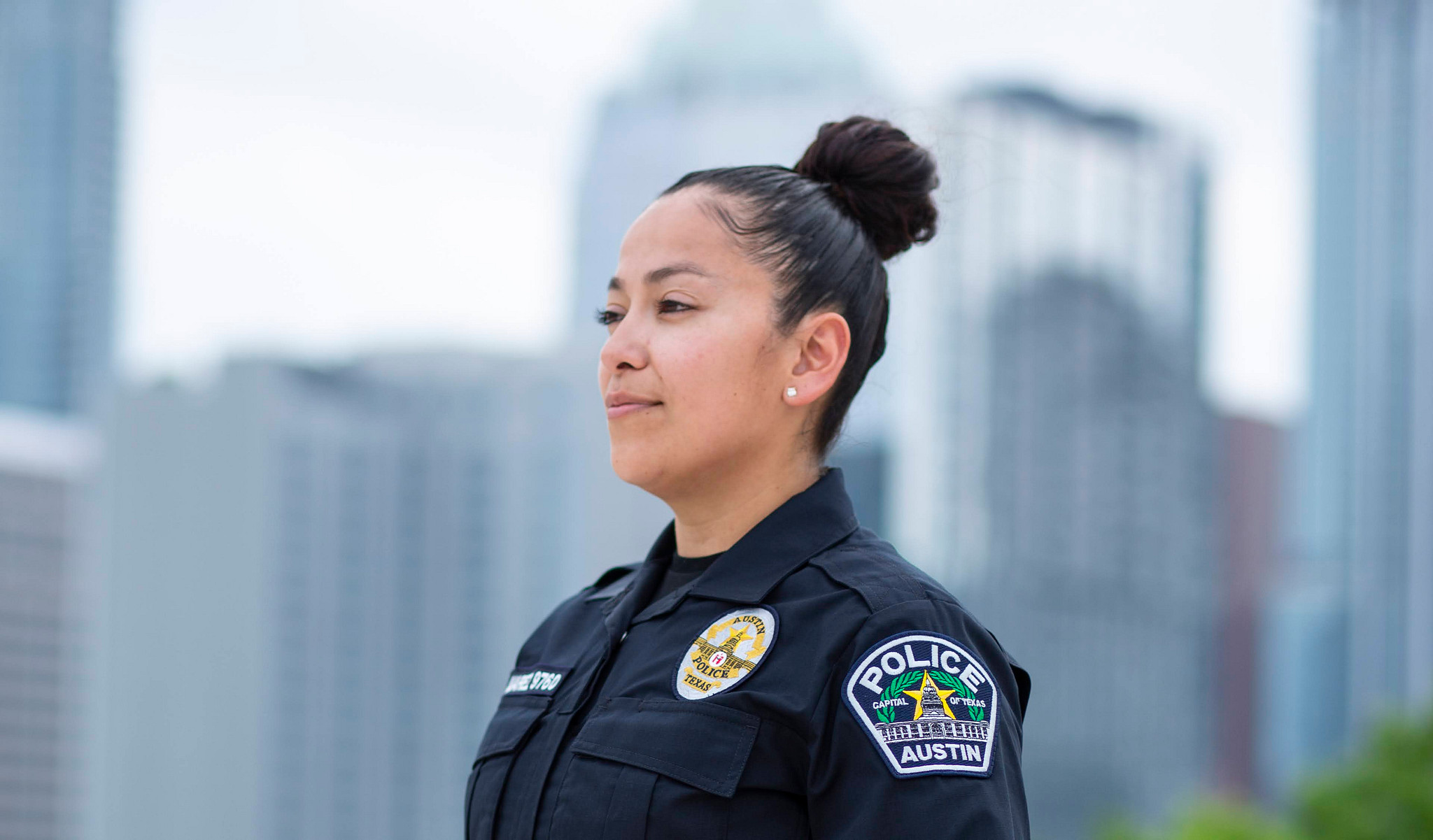 A smiling Austin Police Officer looks out over the Austin skyline.