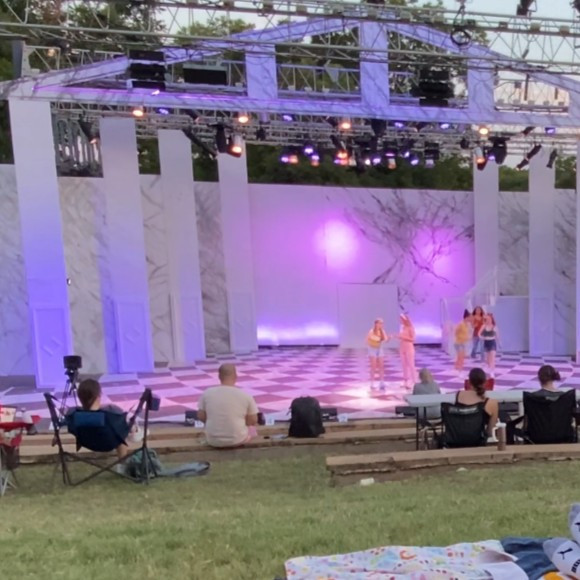 Outdoor stage performance under purple lights at Zilker Hillside Theater.