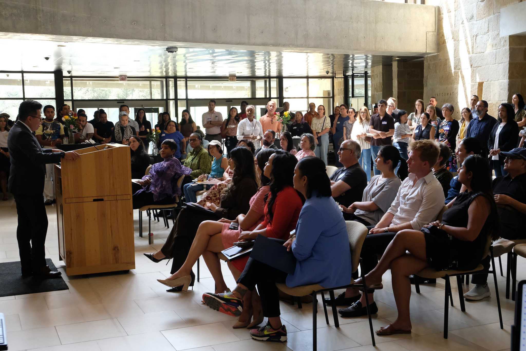 A Latino man addresses the crowd at a podium at Austin City Hall
