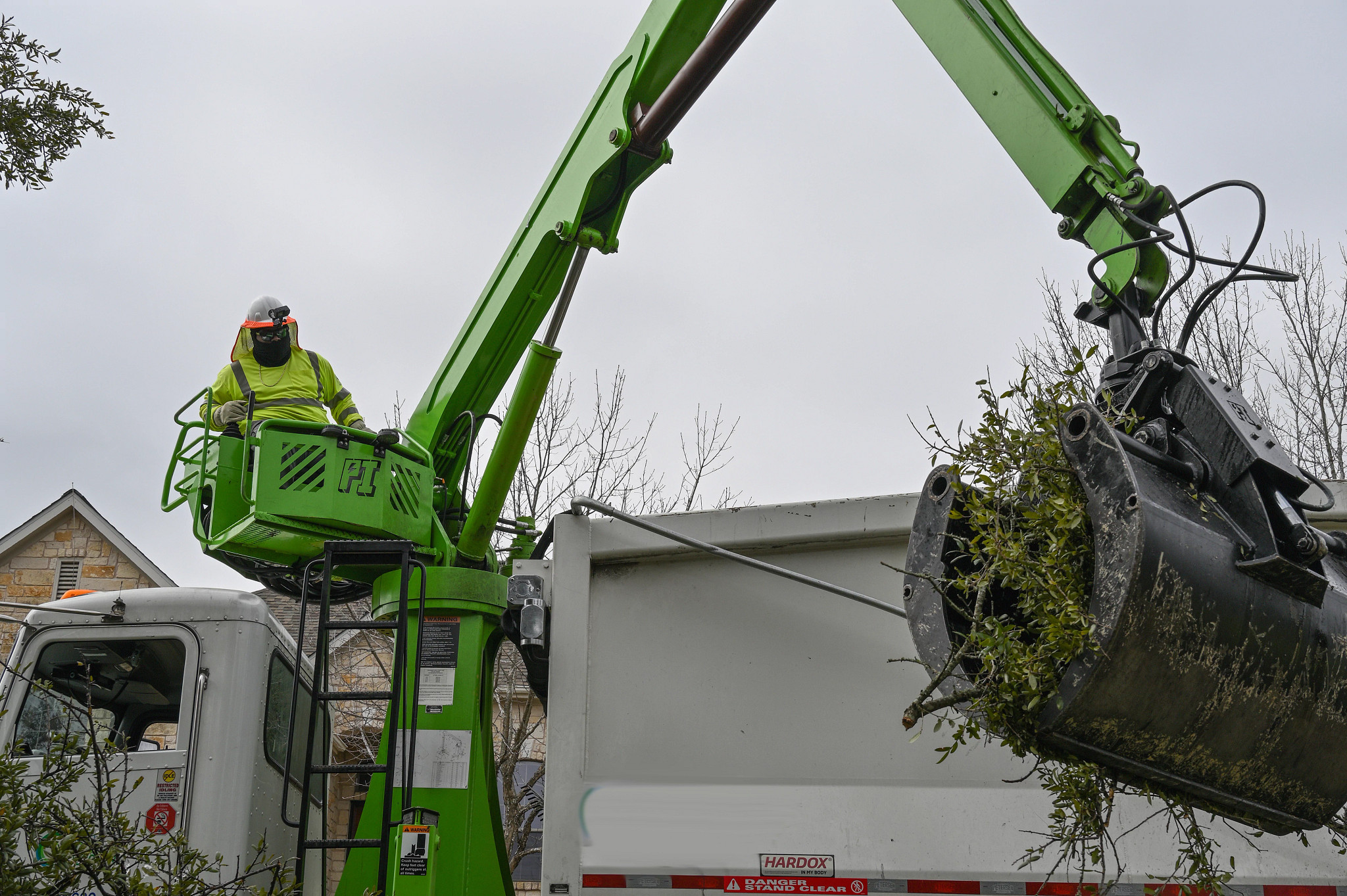 A crane truck picks up tree branches and limbs following a storm.