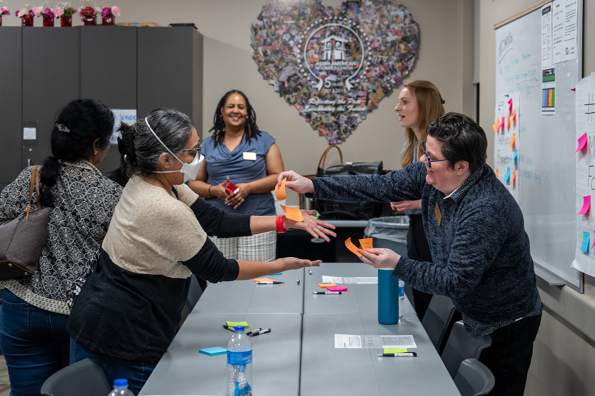 Image of an Austin Police Oversight Community Meeting. An APO staff member exchanges posted notes with a community member.