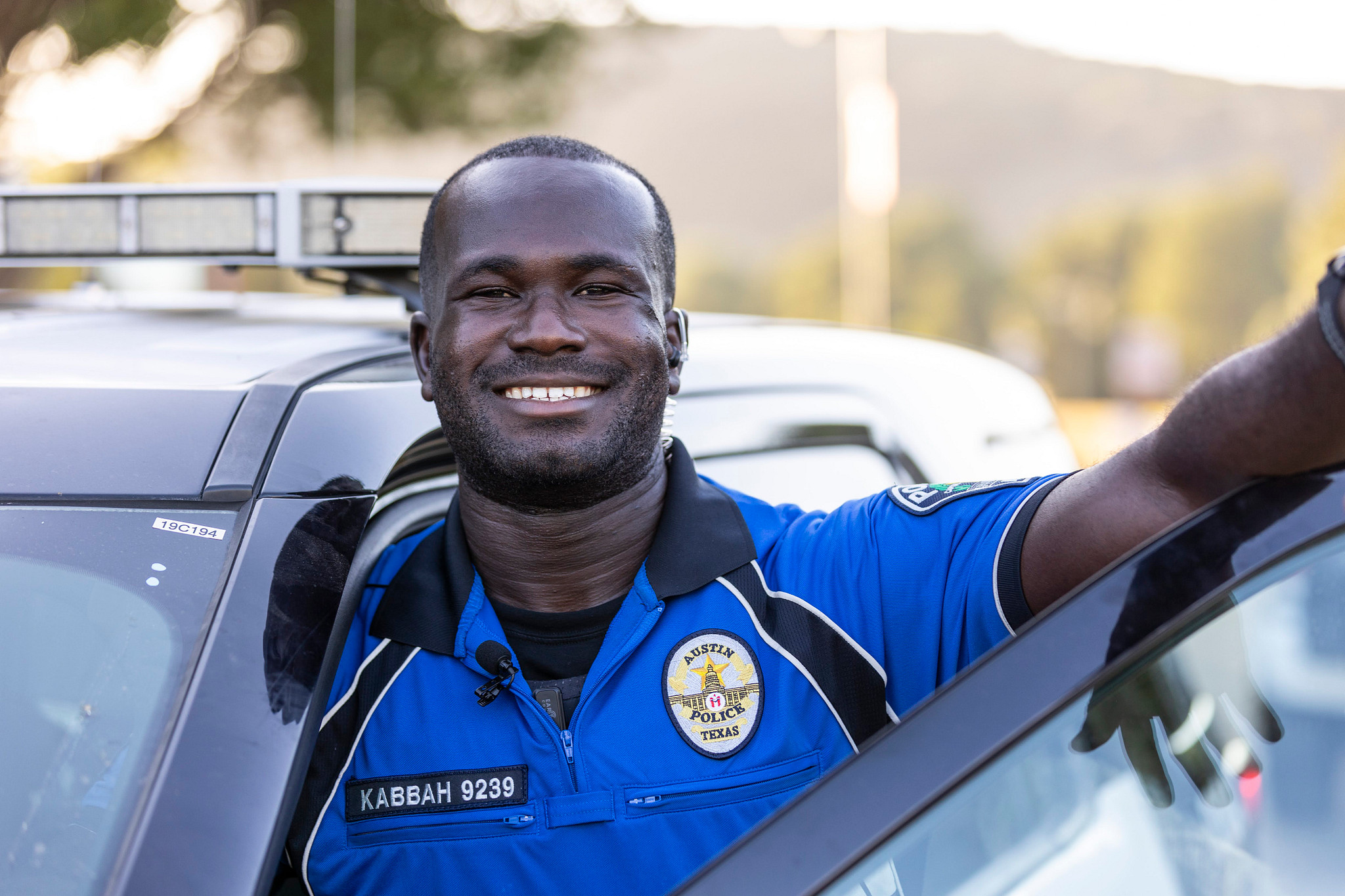 A smiling Austin Police Officer stepping out of their patrol vehicle.