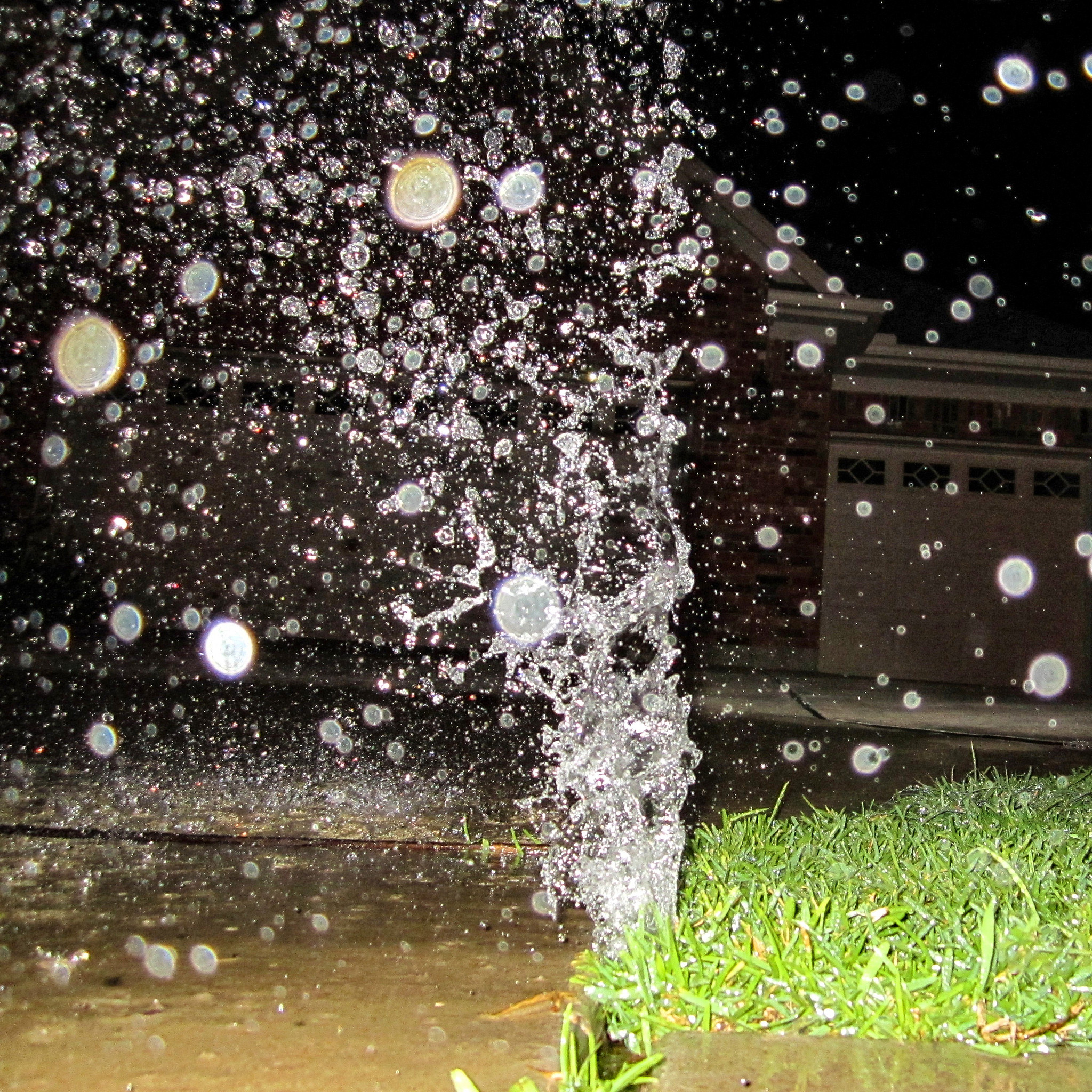 An image of a broken sprinkler head leaking water onto a lawn