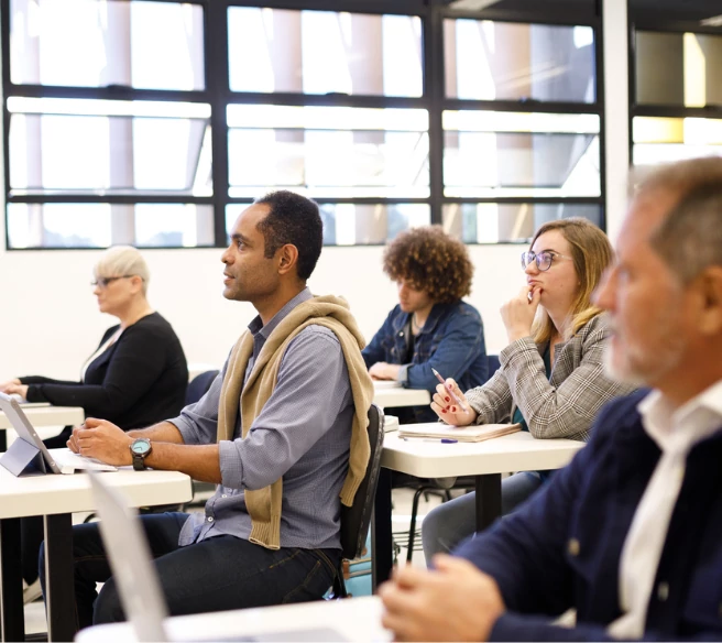 five individuals sitting at computer desks in a classroom