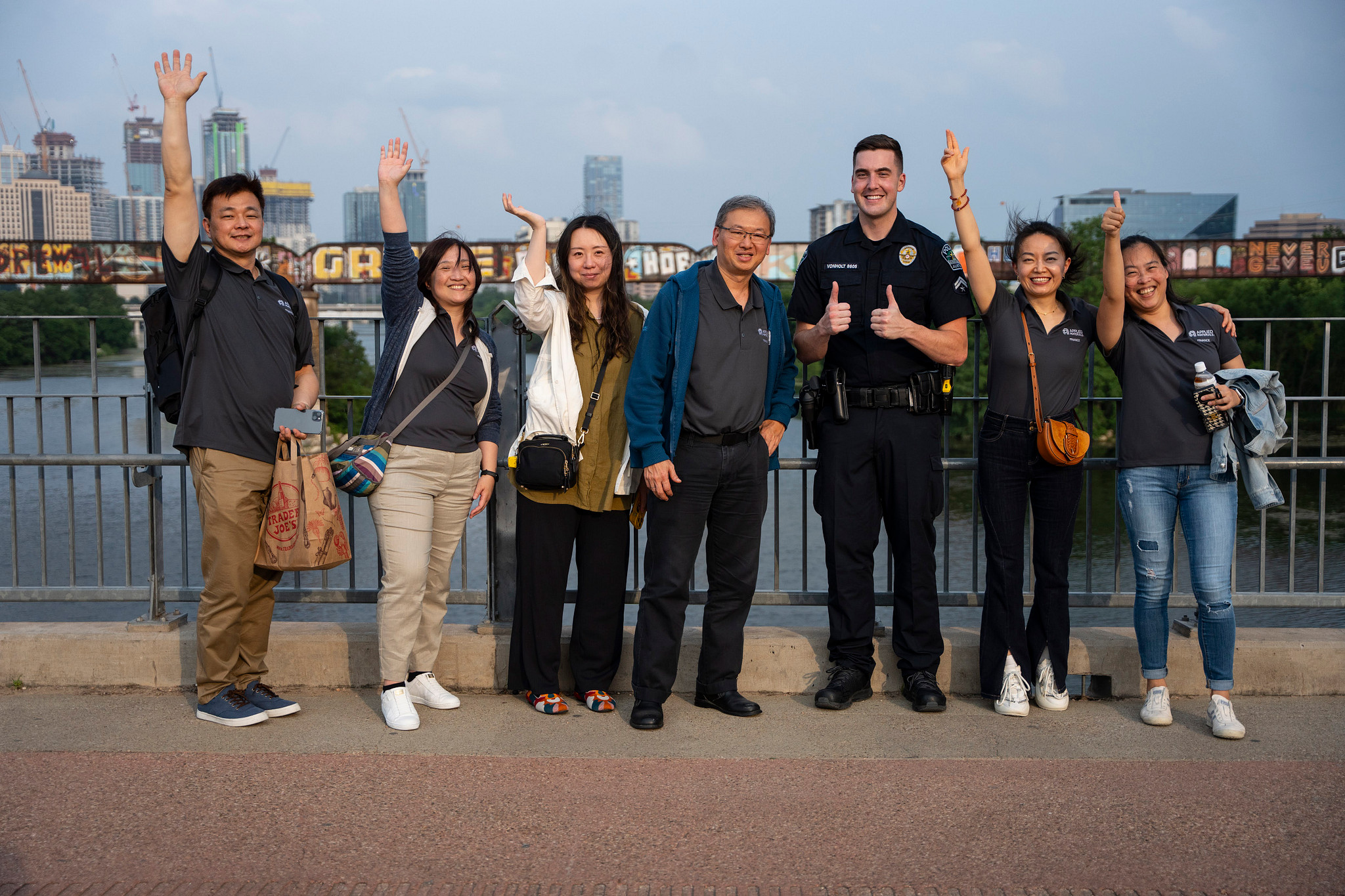 Austin Police Officer and a group of community members smiling and waving on a bridge.