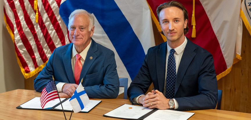 Mayor of Austin, Texas and Tampere, Finland sitting at a desk with Memorandum of Understanding document