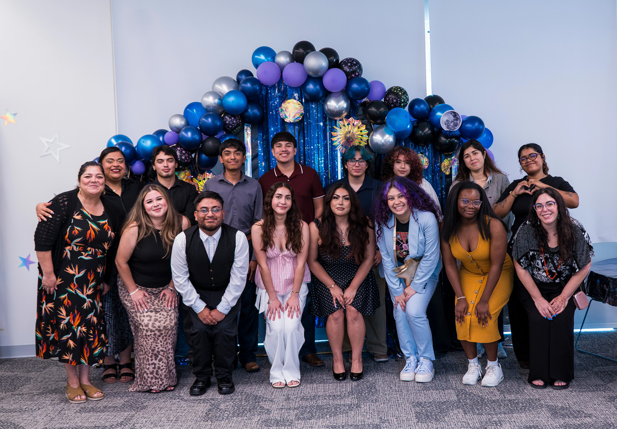 A group of teens standing in front of a large decorative backdrop after a celebration