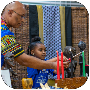 Child lighting Kwanzaa candle at the George Washington Carver